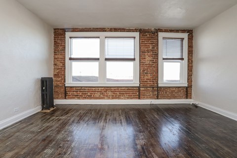 an empty room with a brick wall and two windows